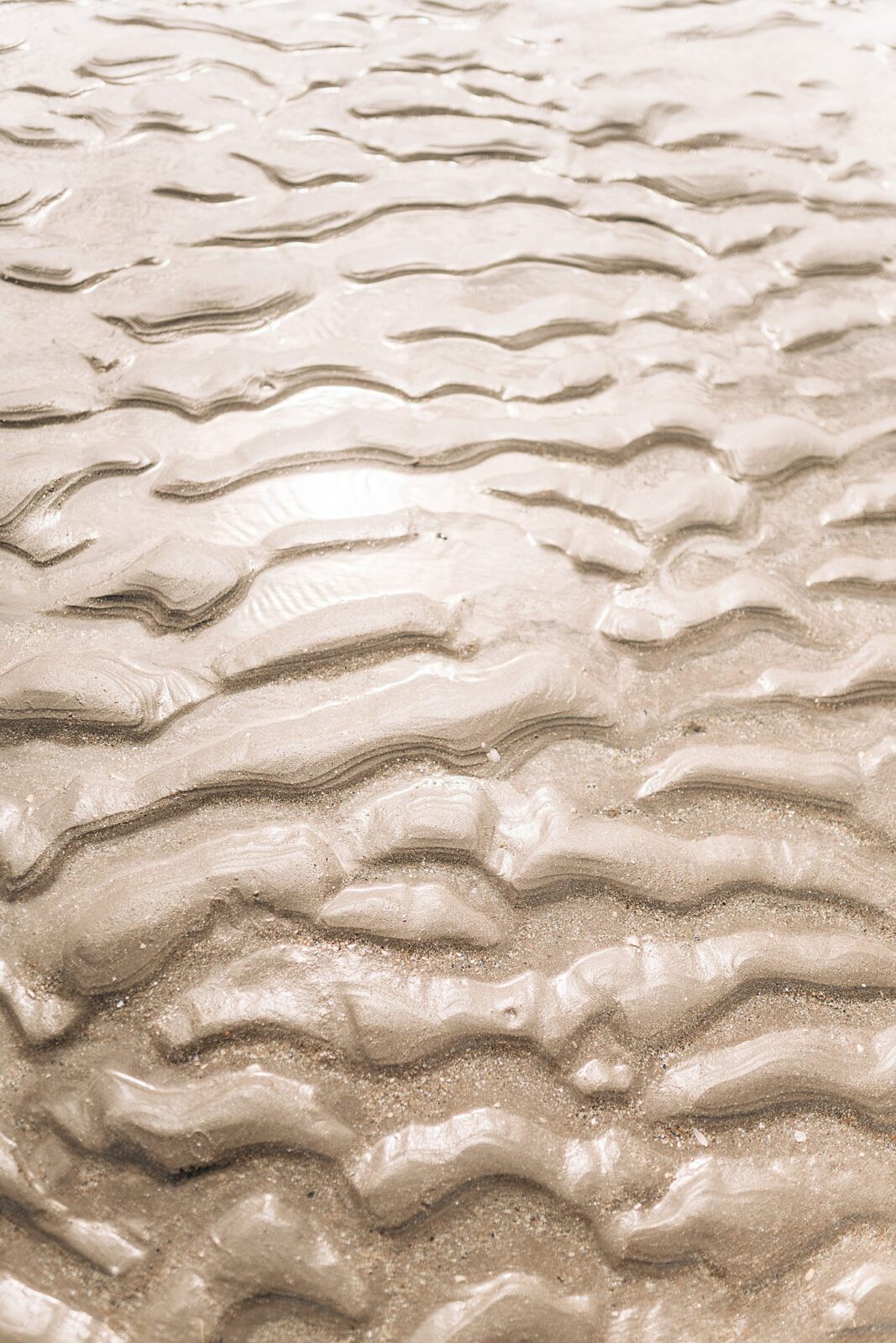 Detail shot of the sun reflecting off the patterns in the sand made by the tides at Inch Beach Ireland, captured by international destination photographer.